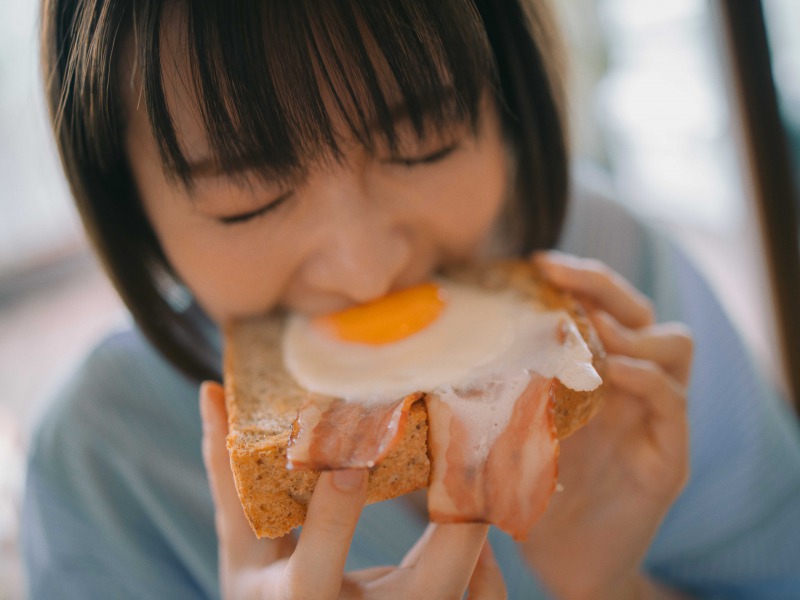 写真は、目玉焼きトーストにかじりつく岡崎紗絵さん(提供:主婦の友社)