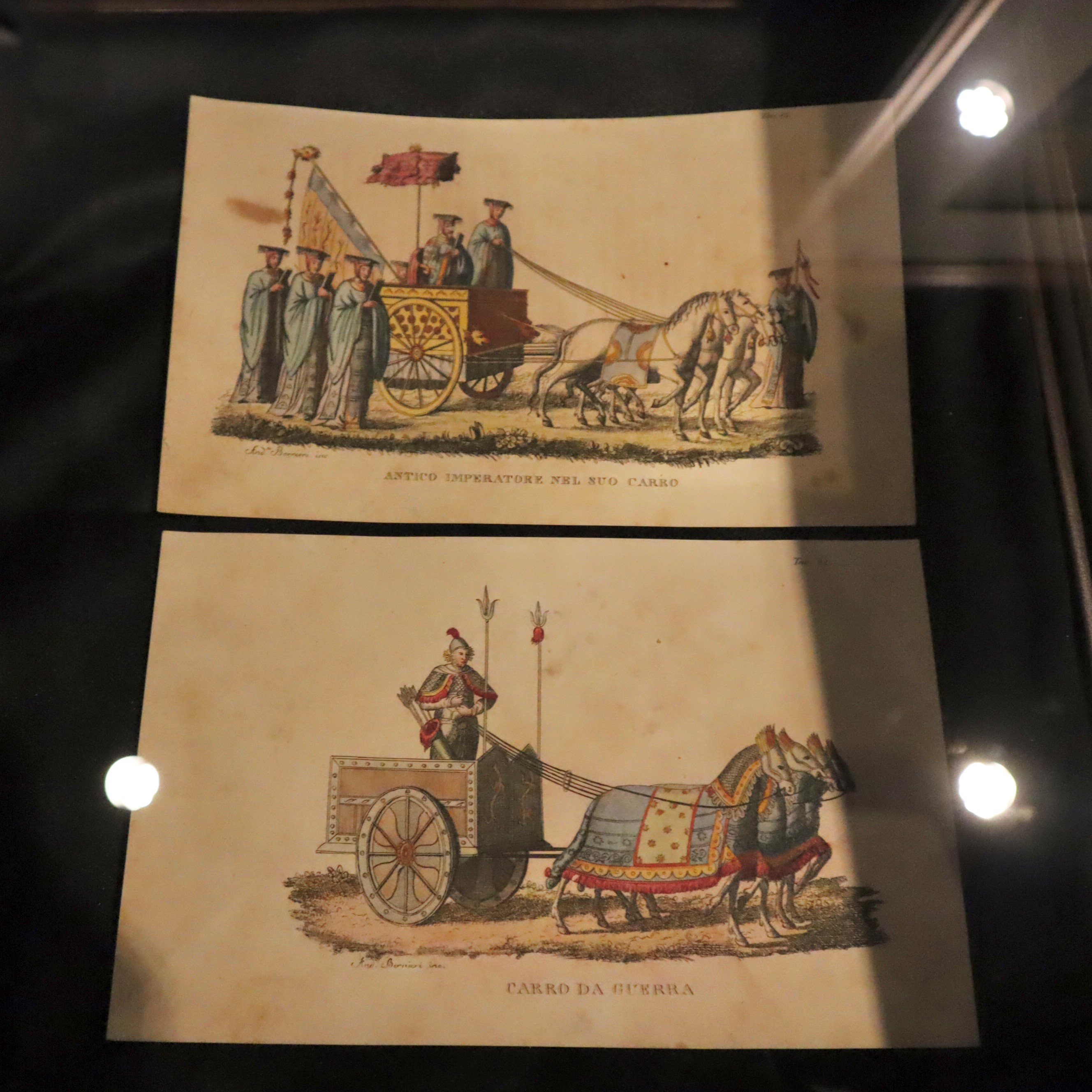 アンダ・ベルニエリ『中国の風景と風俗』（1820年刊）。開催中の企画展「本から飛び出せ！のりものたち」展では、古代中国の戦車の図版も展示されている。上は「戦車に乗った古代の皇帝」、下は「戦車」と、それぞれイタリア語で記されている。